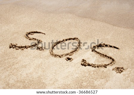 S.O.S. handwritten in sand on a beach