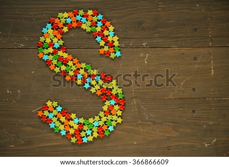 Letter S from alphabet made with star shape candy on a wooden background