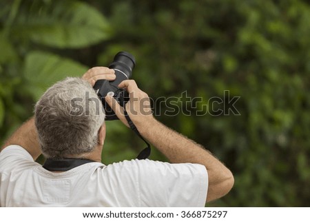 Male photographer capturing a photograph in the rain forest with copy space