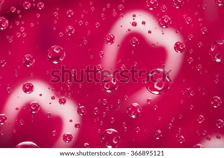 Valentines day background. Heart reflected in the droplets of water. Water droplets on glass with red background.