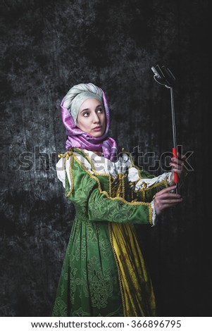 Medieval woman Self holding stick. In the old beautiful yellow-green dress. Historic image. Gothic. Europe