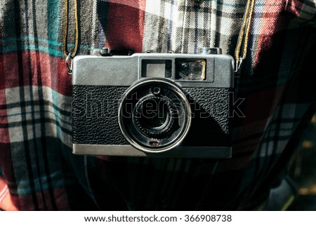 stylish analog photo camera on traveler in sunny forest in the mountains