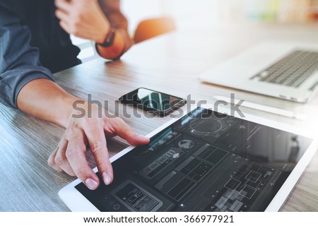 Website designer working digital tablet and computer laptop with smart phone and graphics design diagram on wooden desk as concept Royalty-Free Stock Photo #366977921