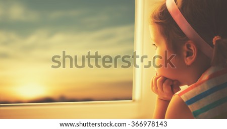 child sad little girl looking out the window at the sunset Royalty-Free Stock Photo #366978143