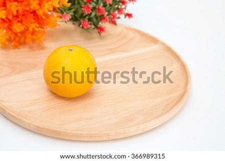 Tangerine in a wooden plate on white background