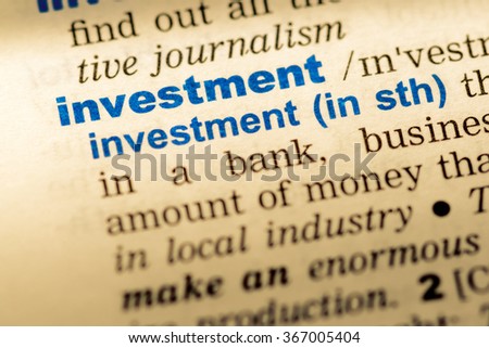 Close-up of word in English dictionary. Investment, definition and transcription