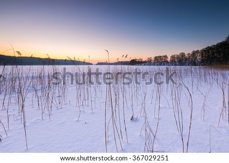 Sunset sky over frozen and snowy lake. Beautiful winter landscape photographed in Poland.