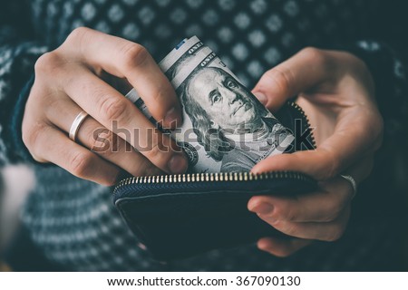 Hands holding us dollar bills and small money pouch. Toned picture Royalty-Free Stock Photo #367090130