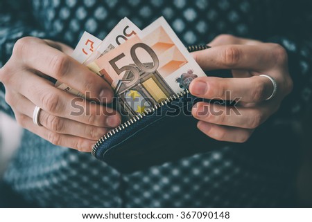Hands holding euro bills and small money pouch. Toned picture