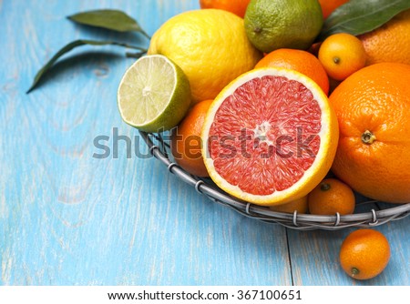 Different fresh citrus fruit in a basket on a blue wooden background Royalty-Free Stock Photo #367100651
