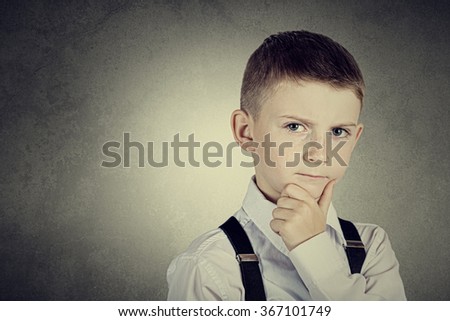 Thinking child-Portrait of a little boy thinking deeply about something with hand on chin looking to camera.
