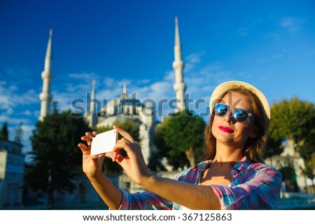 Girl in the hat making selfie by the smartphone on the background of the Blue Mosque, Istanbul. Turkey