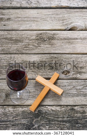 wooden cross and glass of red wine on old wood table