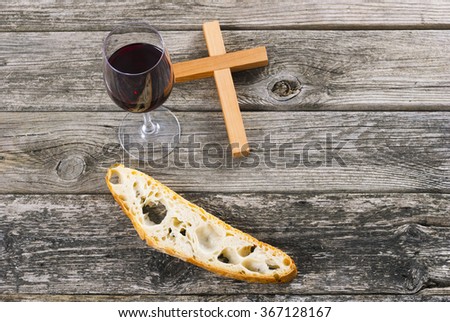 wooden cross and red wine with a slice of bread on old wood table