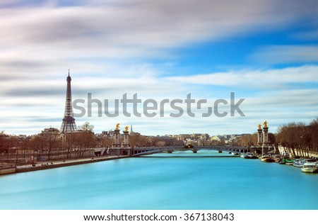 Beautiful colored long exposure view of the river Seine in Paris, with the Eiffel tower in the background, on a cloudy winter day 