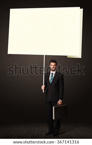 Young businessman holding a big, white post-it paper
