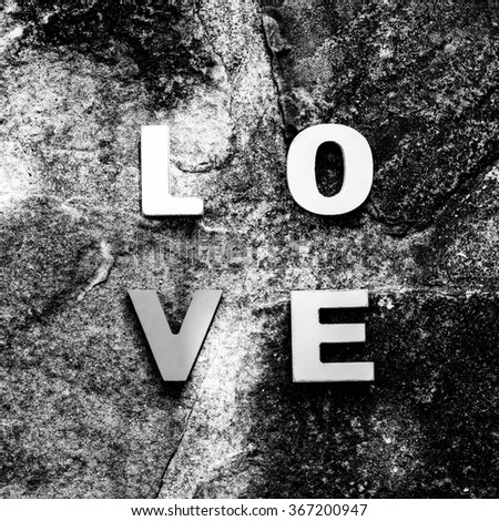 word love made up of colorful wooden letters on a stone floor, top view. February 14, Valentine's Day. Black and white.