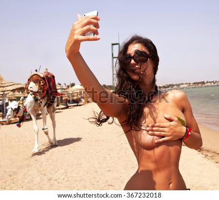 young beautiful woman on the beach makes a picture on the background of the camel