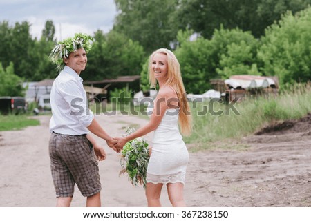Happy young couple with a bouquet and a wreath embracing and kissing, lifestyle, love, relationships