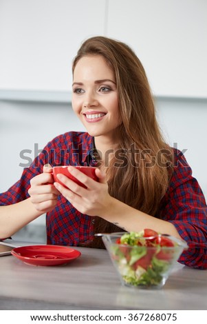 young woman eating fresh salad in modern kitchen