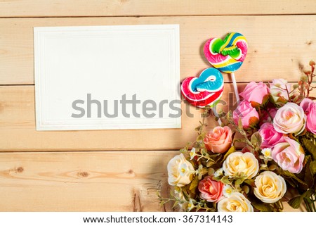 Pastel color roses flowers and empty tag for your text with heart shape candy on wooden background