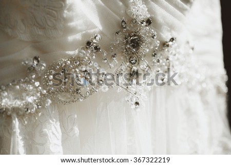 Magnificent snow-white wedding bridal dress with beaded embroidery in the room for charges bride preparing for the wedding ceremony.