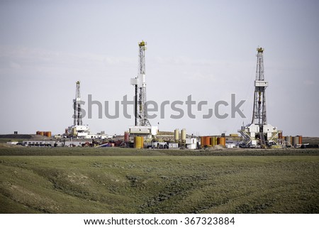 Three hydro-fracking derricks sitting on a plain. Royalty-Free Stock Photo #367323884
