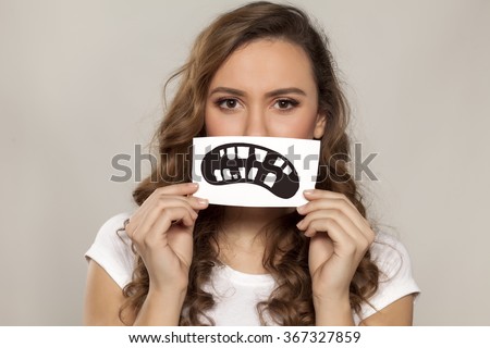 sad girl with a defective teeth painted on paper over her mouth Royalty-Free Stock Photo #367327859