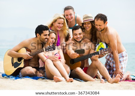 Young guys with guitar making mutual photo at sandy beach