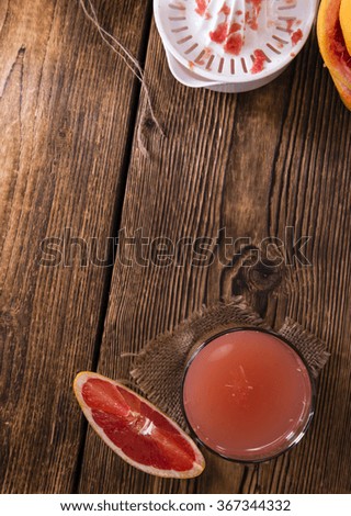 Fresh Grapefruit Juice on rustic wooden background (close-up shot)