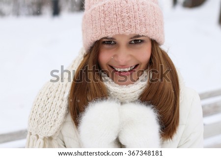 Happy beautiful young woman sitting on the wooden bench in wintertime outdoor