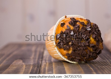 One laying on wooden table sweet dessert yummy muffin in paper form decorated by chocolate crumb fattening meal baked food closeup studio copyspace, horizontal picture