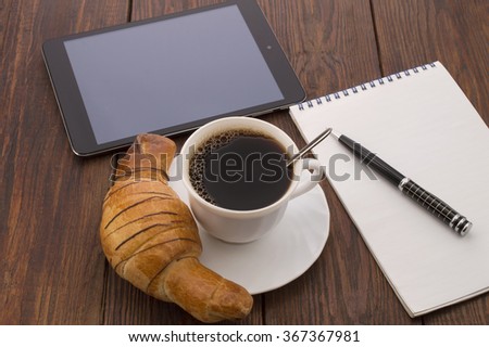 breakfast with cup of black coffee, croissants, the tablet and notebook with pen isolated on white background