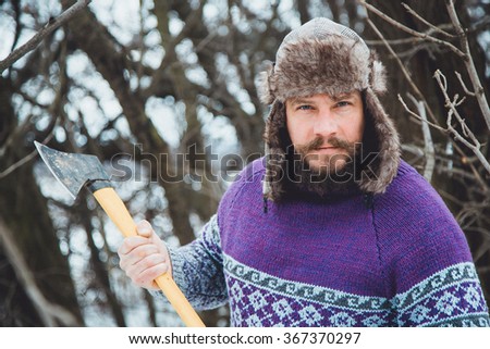 Portrait of a bearded evil forester. Portrait of a Bearded Man with an ax in his hand. Brutal bearded man with an ax. North bearded man with an ax in the woods. 