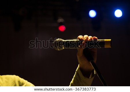 Image the announcer speaks into a microphone. Close up of microphone in concert hall or conference room