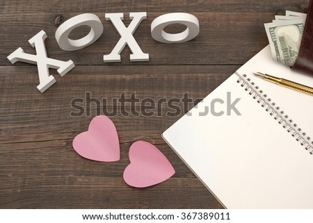 Love Kiss Concept. Sign XOXO, Two Paper Pink Sticker Hearts, Gold Pen, Blank Page, Male Wallet With Dollar Cash On The Wood Background With Copy Space, Top View