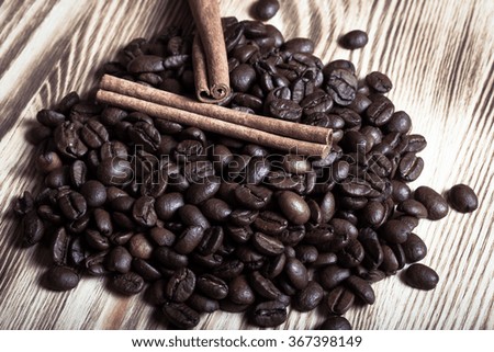 Pile of coffee beans with cinnamon on wooden table for background. Selective focus. Toned.