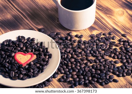 Coffee beans and coffee in white cup on wooden table for background. Toned.