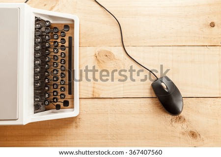 The picture shows an old typewriter connected to a computer mouse