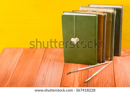 Stack of hardback books, diary on wooden deck table and yellow background. Back to school. Copy Space. Education background