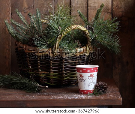 Winter still life with fir-tree and pine branches, a paper glass with tea and the cone against a dark background. Royalty-Free Stock Photo #367427966