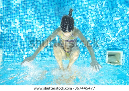 Blurred underwater: child swims in pool, happy active girl has fun under water, kid sport on family vacation
