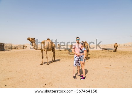 Couple standing in a desert near camel