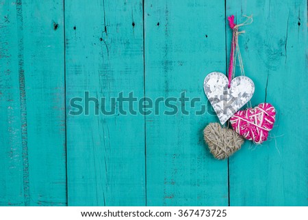 Rope hearts and silver tin heart hanging on antique rustic teal blue wood door; Valentine's Day and love concept