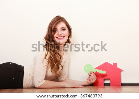 Smiling young woman girl holding paper house and key dreaming about new home. Housing and real estate concept.