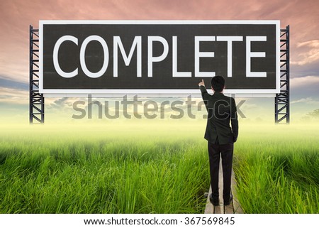 business man standing on wood bridge between rice field and pointing with large sign of complete (business concept)
