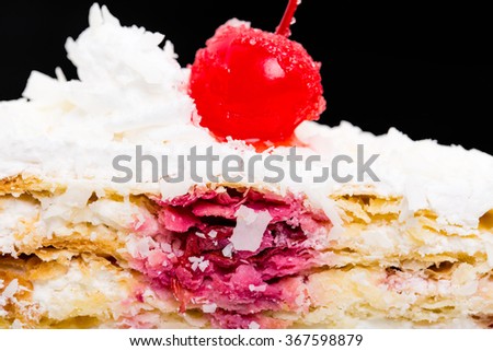 Delicious cake with cocktail cherry and coconuts. Macro. Against black background.