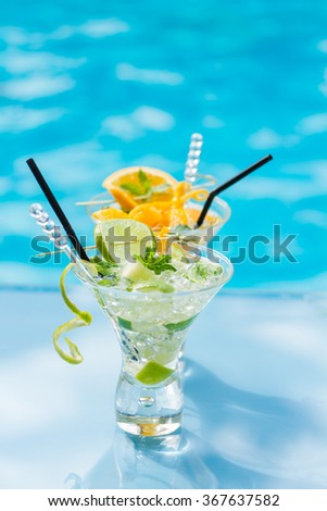 Mohito mojito drink with ice mint, orange and lime near swimming pool
