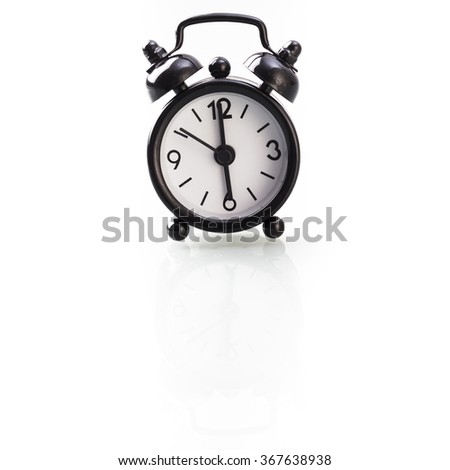 Retro style alarm clock showing six o'clock, isolated on white background with reflection.