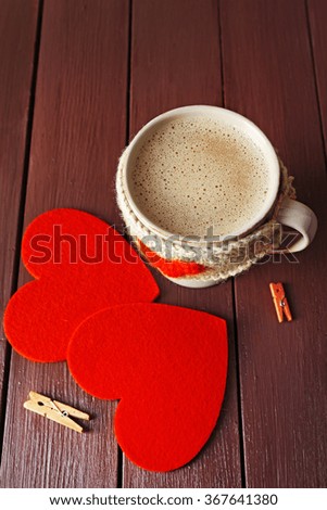 Coffee cup with milk, clothespins and two hearts on wooden background closeup